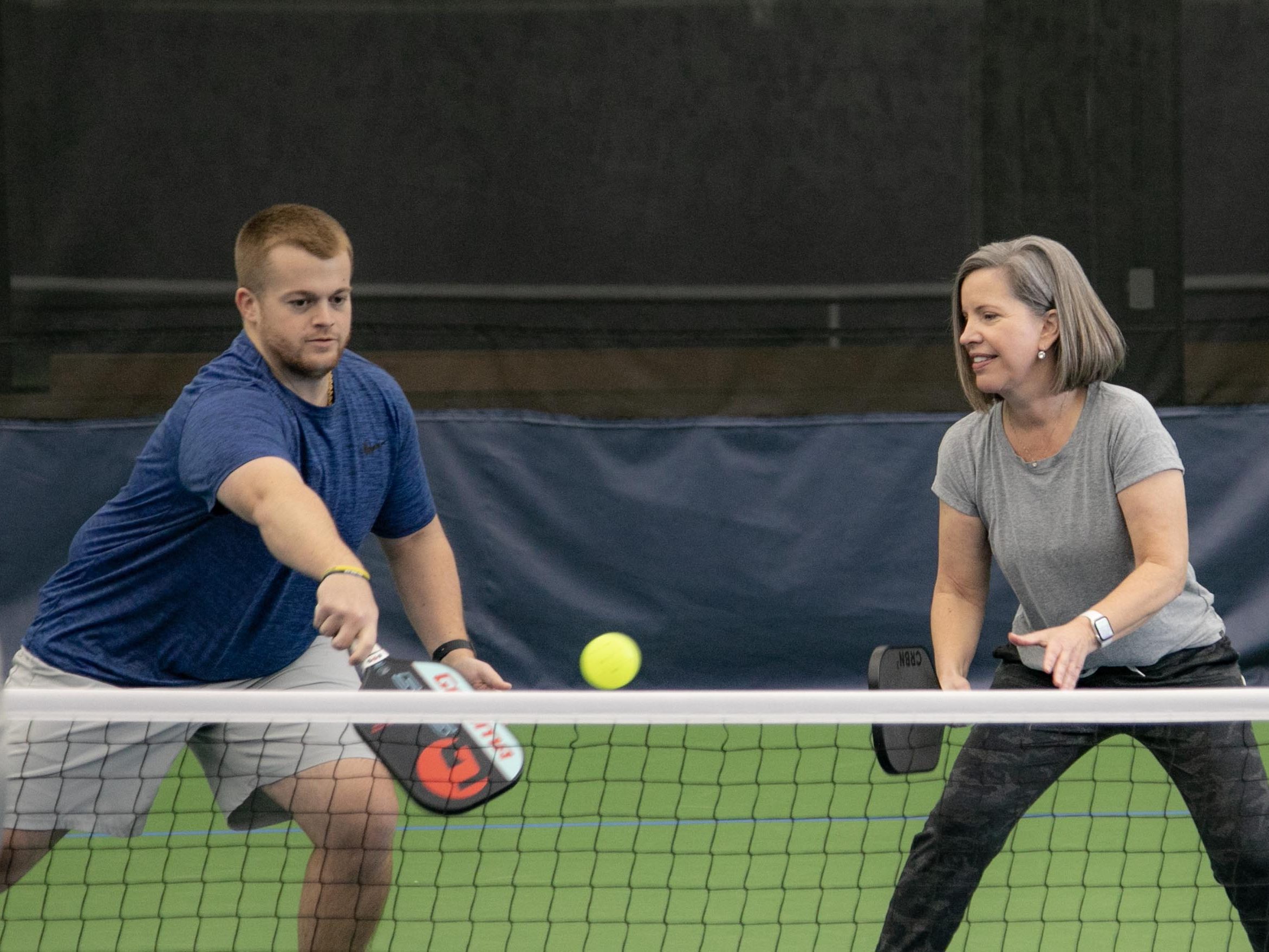 Four pickleball players concentrating on the pickleball at the net.